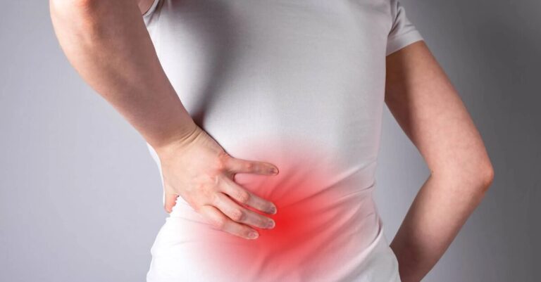 Woman holding her lower back with back pain highlighted in red